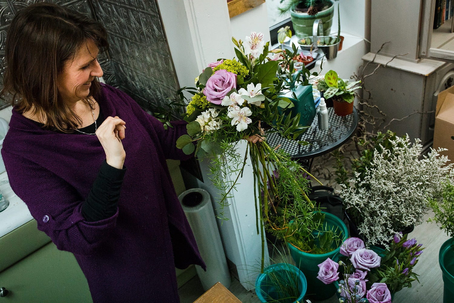 Purple, green, and white fresh floral stems. Elise putting together a bouquet at the Village Green Flower Shop.