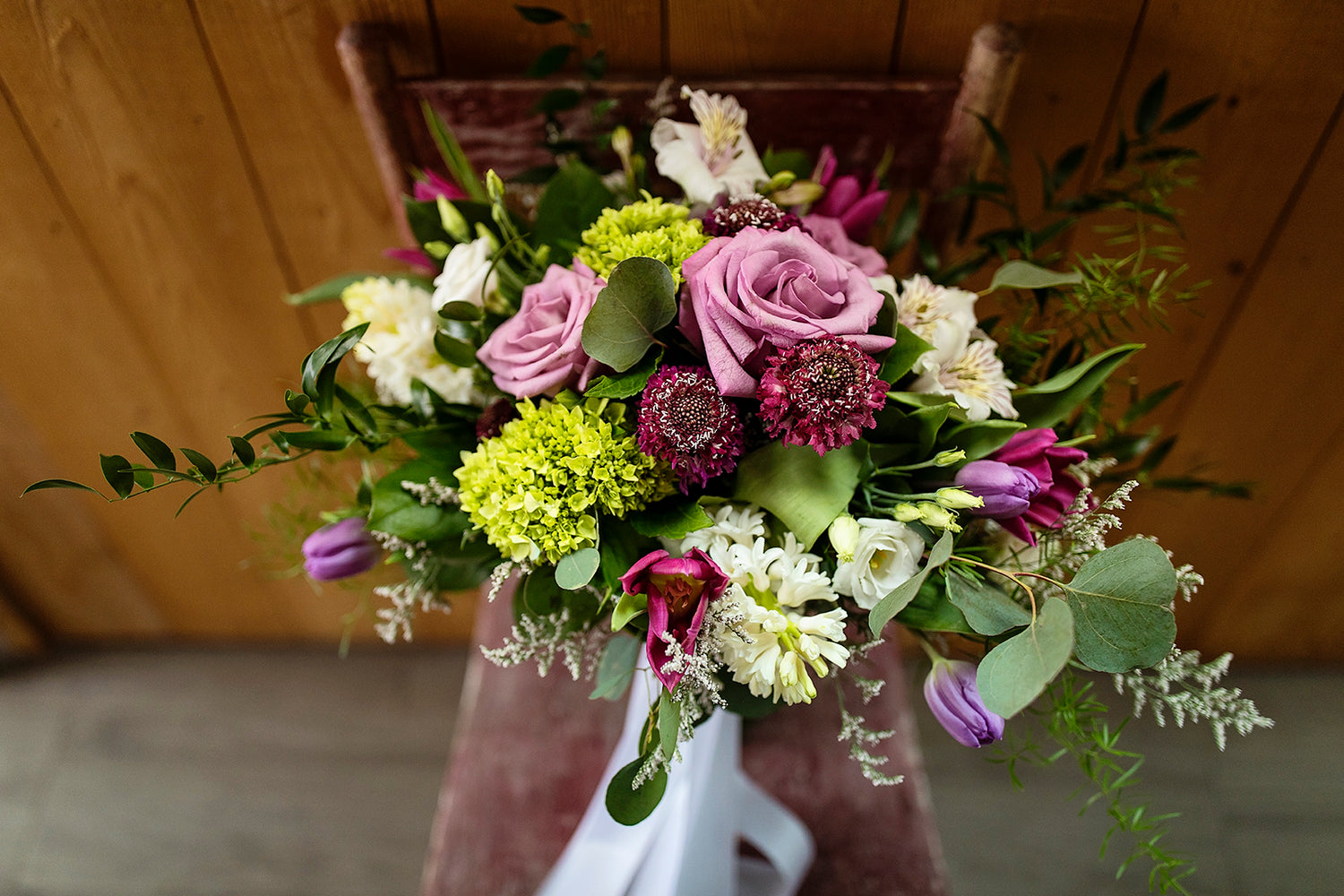 A finished bouquet created with green, white, purple, and pink flowers.